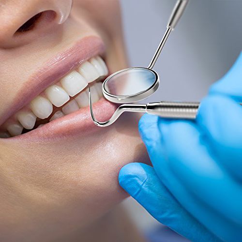 Close-up of a dental checkup using a mirror and probe